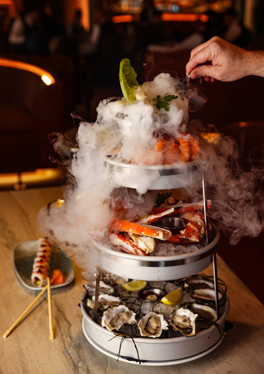 Corporate Chef Ian Rough pours water into the dry ice component of the Smoking Shellfish Tower, ...