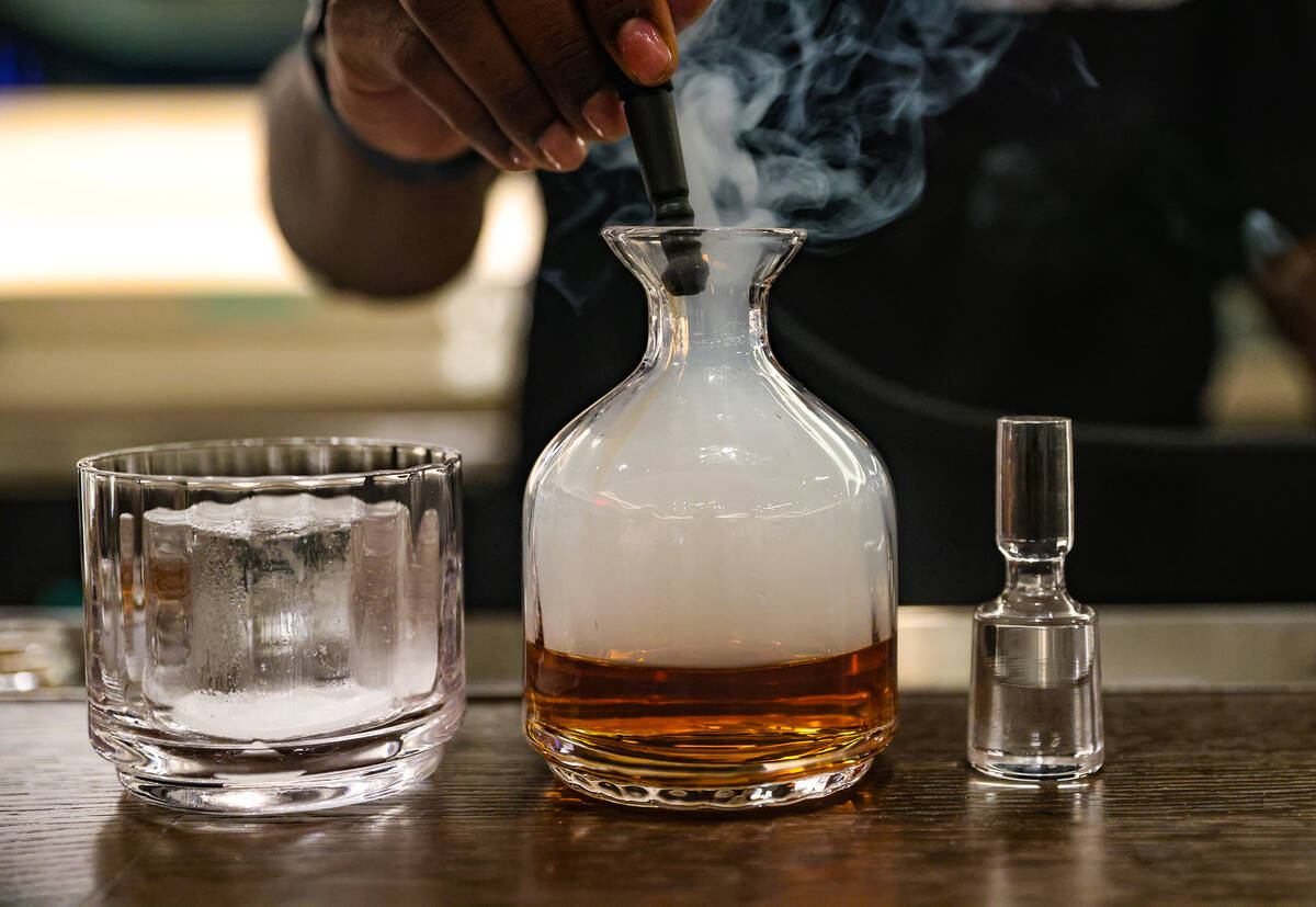 Beverage Operations Manager Josh Dunson prepares smoke for the Old Fashioned at Ocean Prime, an ...