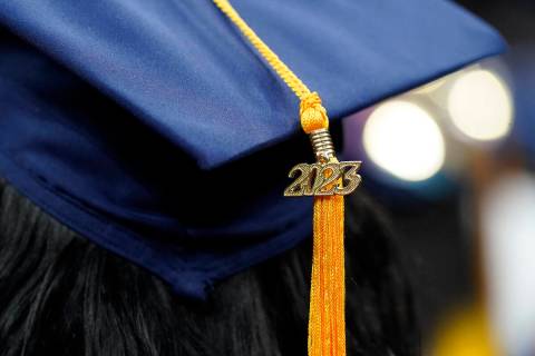 FILE - A tassel with 2023 on it rests on a graduation cap as students walk in a procession for ...