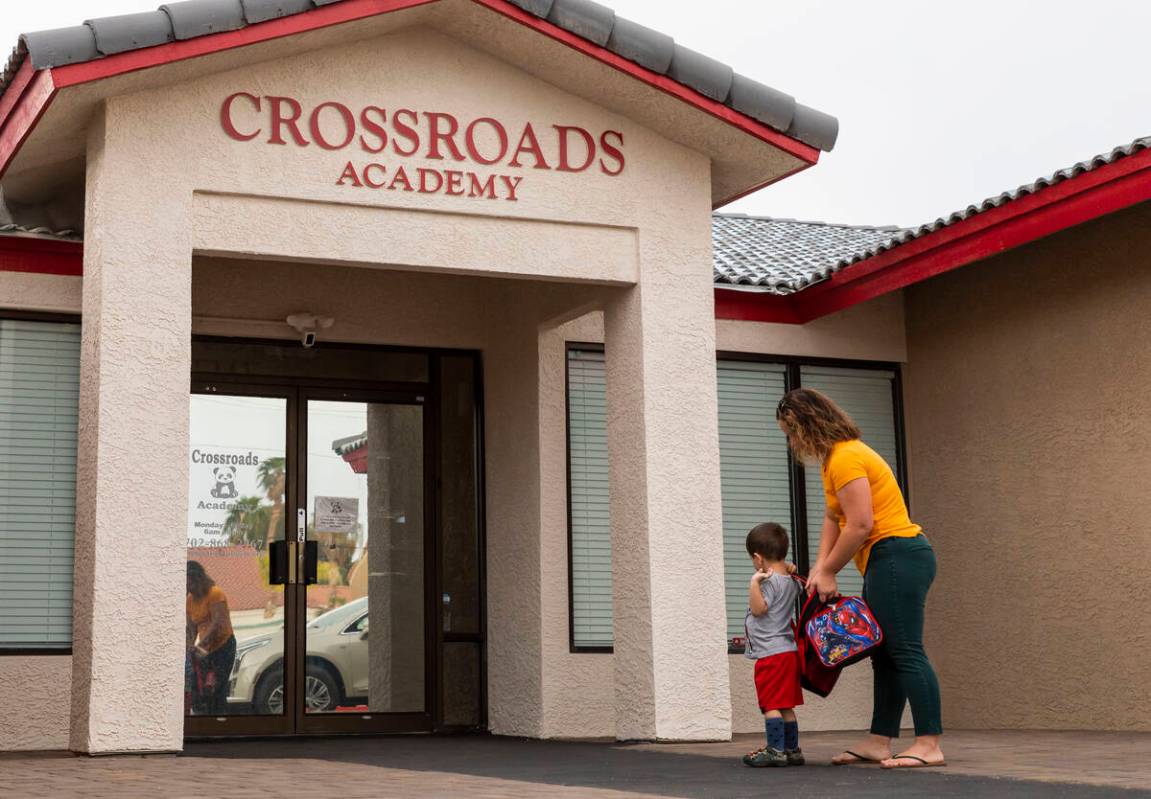 A mother walks her son into the Crossroads Academy preschool on Wednesday, June 7, 2023, in Las ...