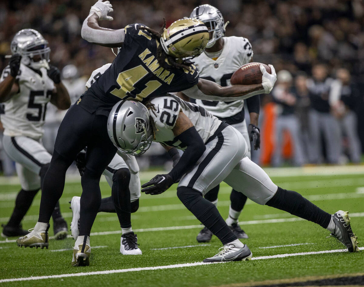 New Orleans Saints running back Alvin Kamara (41) reaches over Raiders safety Tre'von Moehrig ( ...