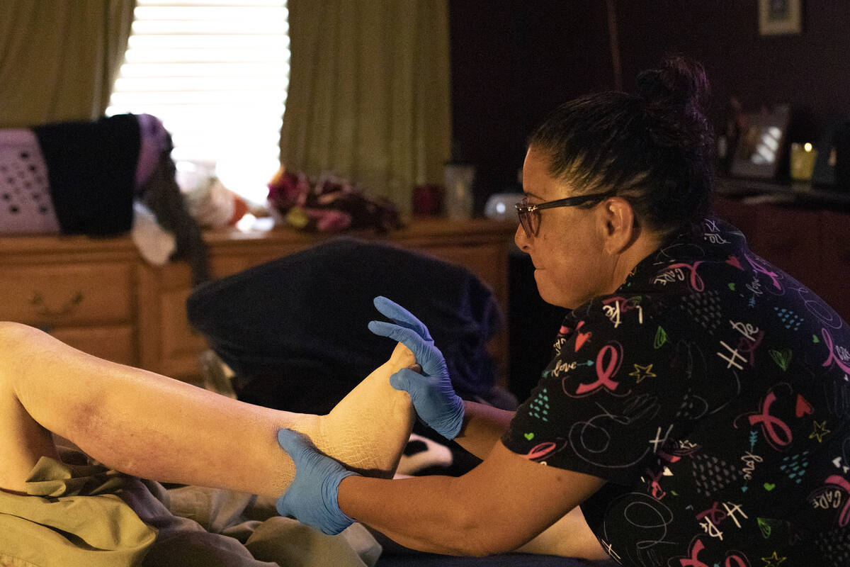 Personal care aid Irma Nuñez stretches her client Thomas Draa's legs on Wednesday, April 1 ...