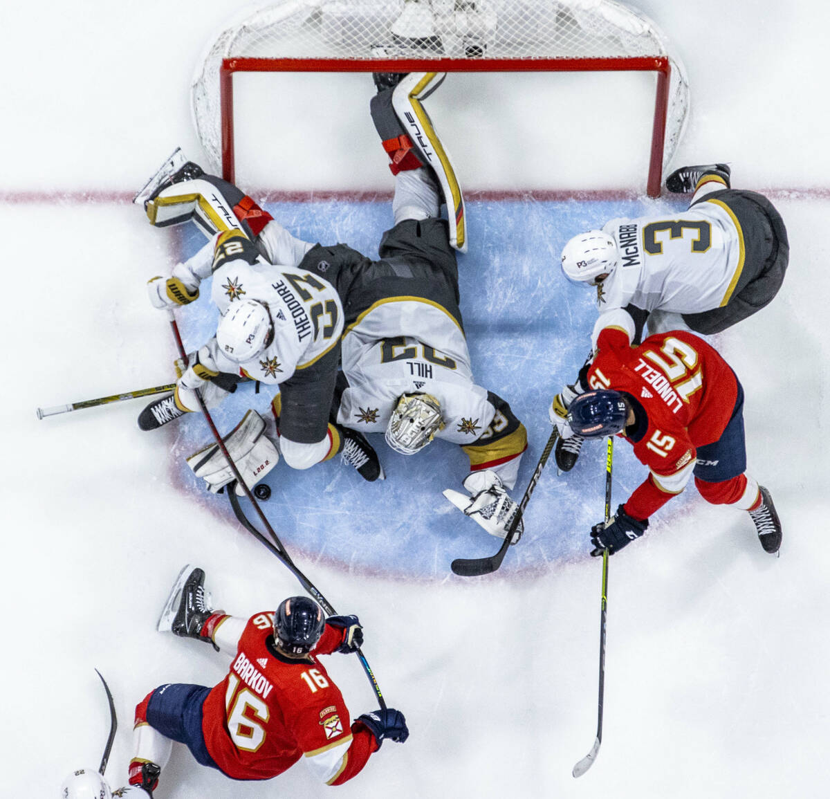 Golden Knights goaltender Adin Hill (33) and defenseman Shea Theodore (27) fight off a shot fro ...