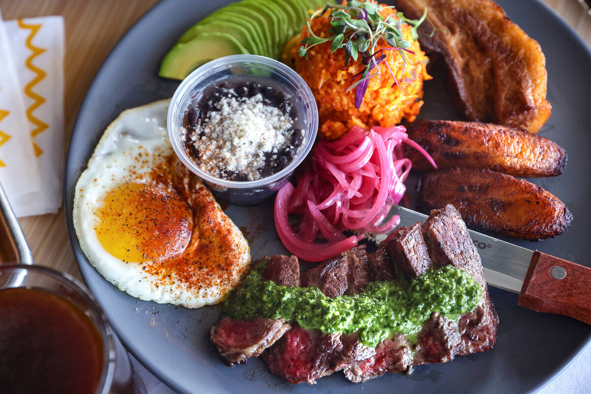 The bandeja paisa, made of eight ounces flat iron steak, crispy pork belly, fried maduros, a su ...