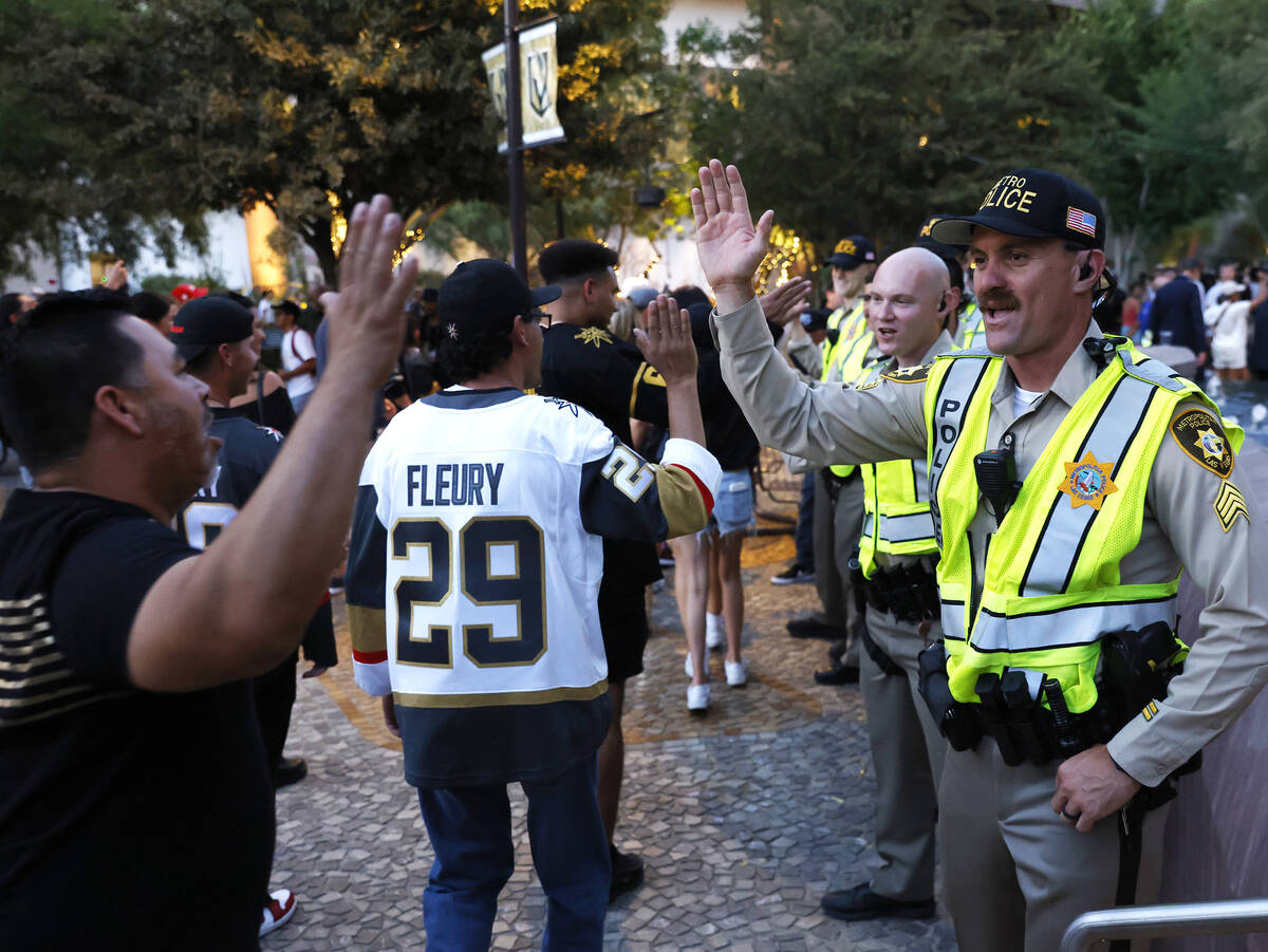 Golden Knights fans and Las Vegas police officers exchange high-fives after the team's Stanley ...