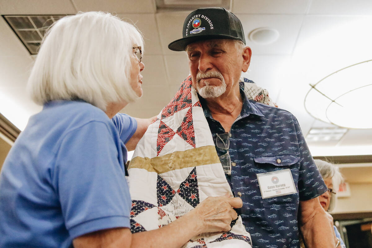 Gene Harvey, right, gets emotional as a custom quilt is draped around him by Quilts of Valor Fo ...