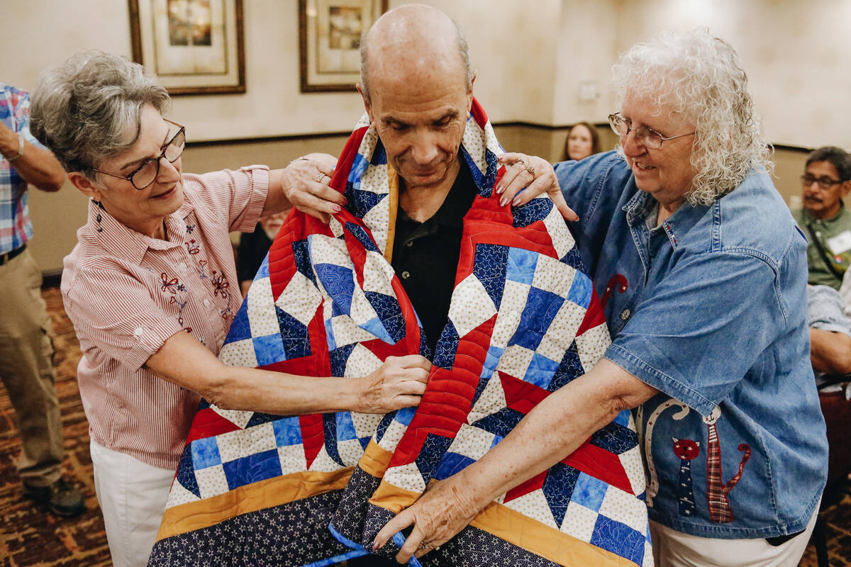 Martin Renert is draped with a handmade quilt by Quilt of Valor foundation volunteers Carole Ne ...