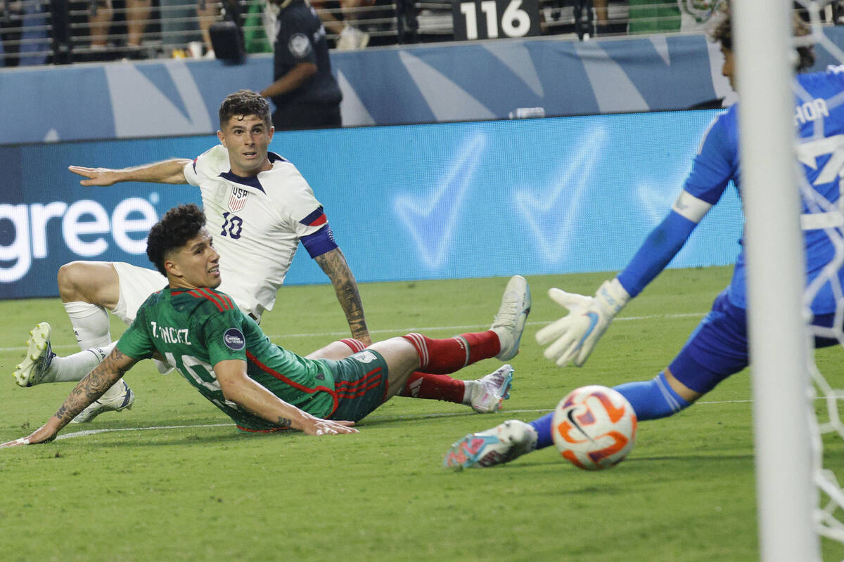 USA’s Christian Pulisic (10) scores a goal against Mexico goalie Guillermo Ochoa (13) as ...