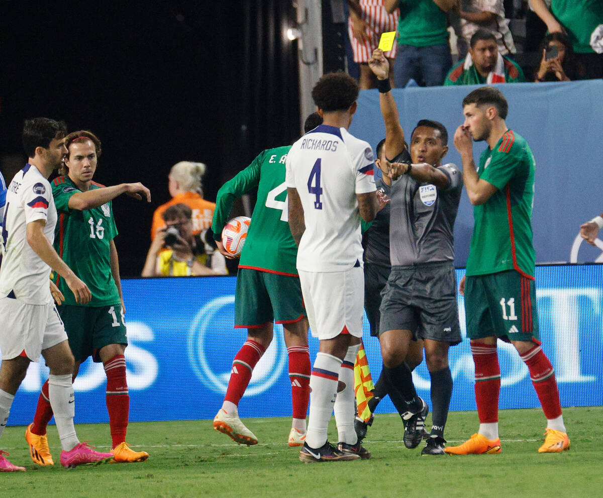 A referee shows a yellow card during the second half of a CONCACAF Nations League semifinal soc ...