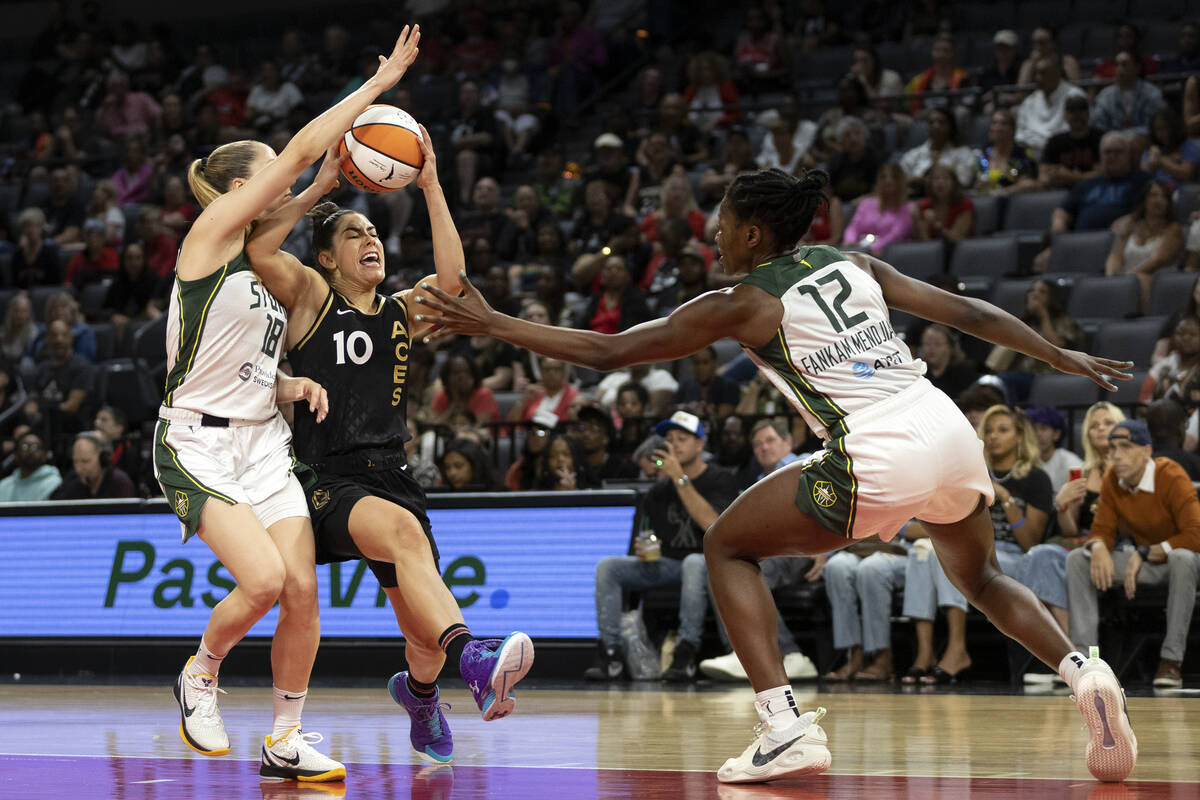 Las Vegas Aces guard Kelsey Plum (10) drives toward the hoop between Seattle Storm guard Ivana ...