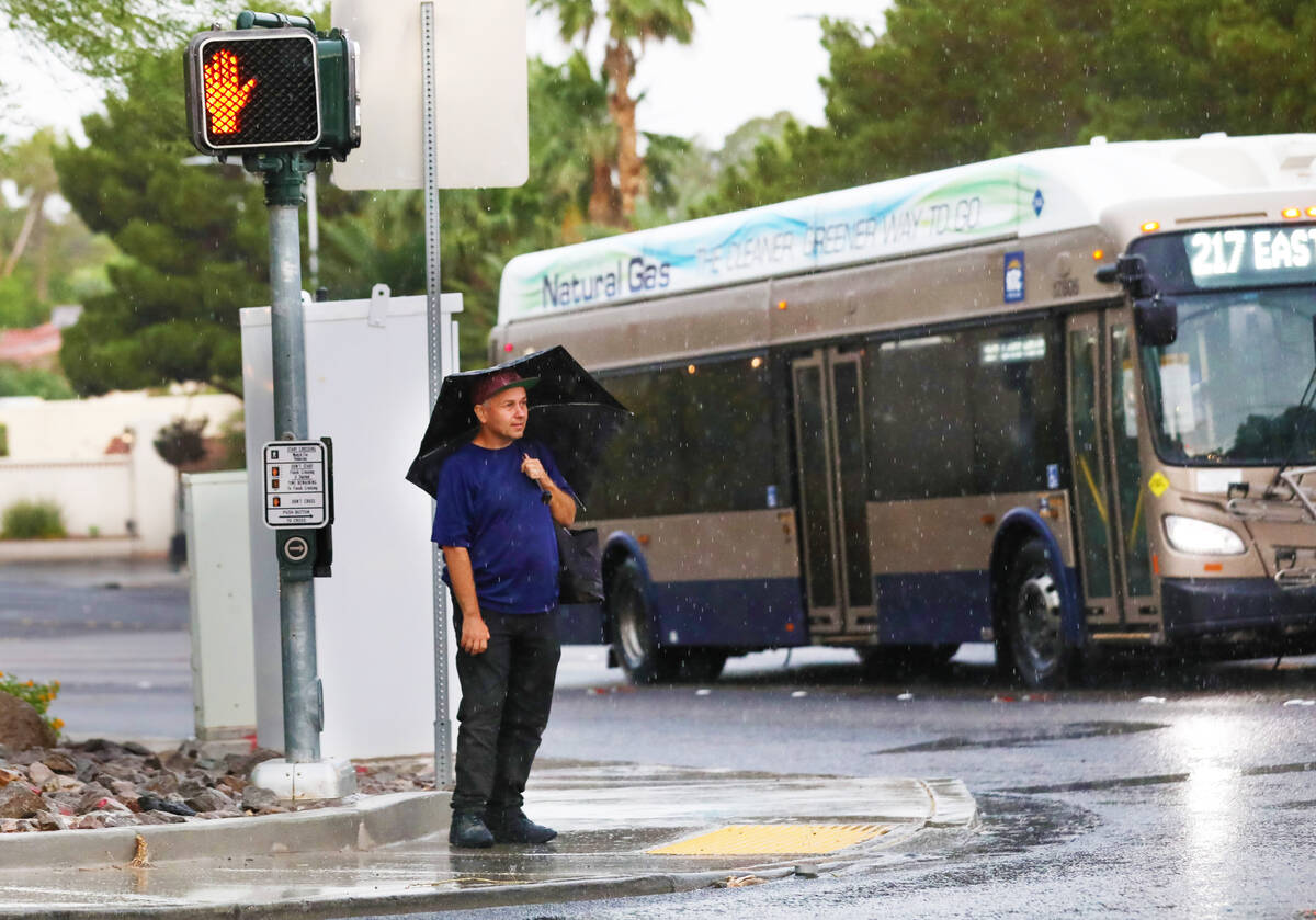 A man waits to cross Pecos road during an early morning rain storm on Friday, June 16, 2023, in ...