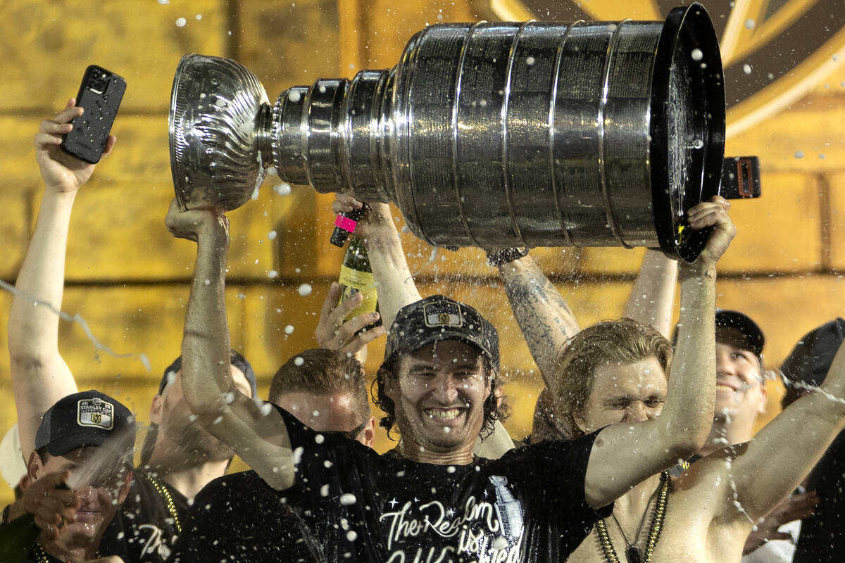 Golden Knights right wing Mark Stone (61) is showered with champagne while holding up the Stanl ...
