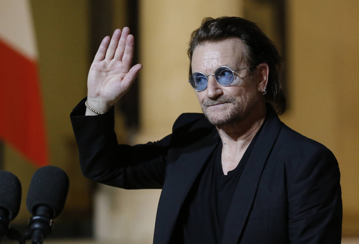 Bono waves good-bye to the media after a meeting with French President Emmanuel Macron at the E ...