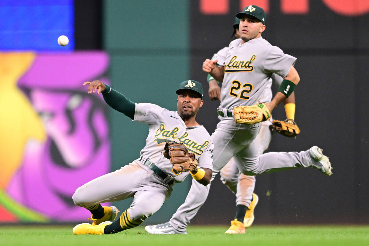 Oakland Athletics second baseman Tony Kemp, front, throws after catching a ball hit by Clevelan ...