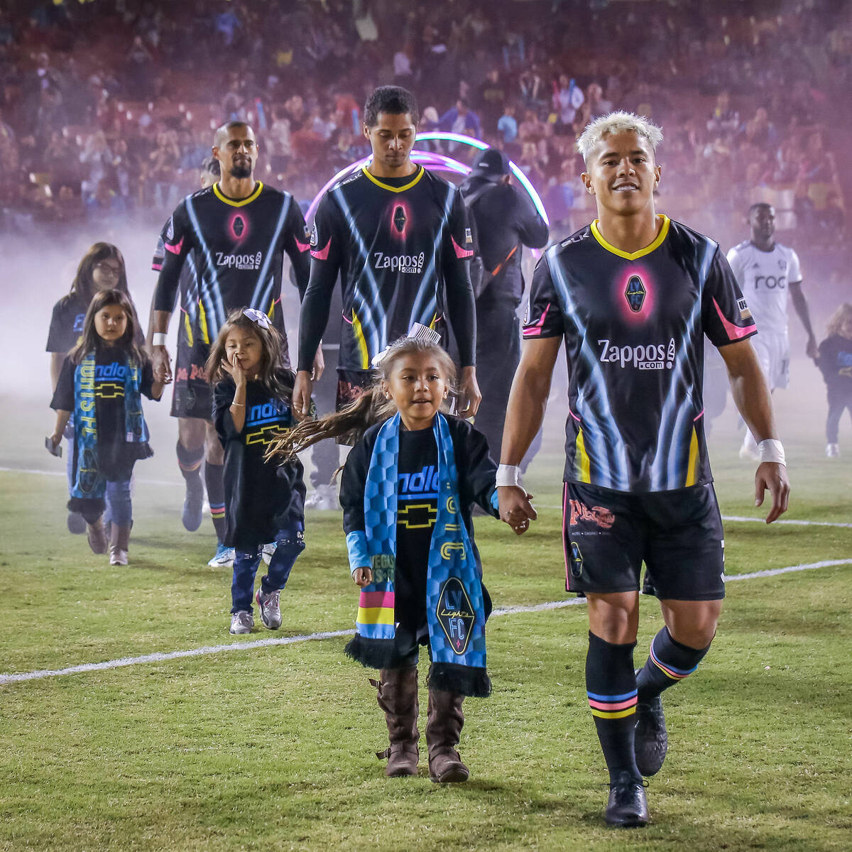 Young fans hold hands with Lights FC players as they walk onto the field in an undated photo. ( ...