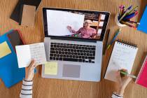 High angle view of video conference with teacher on laptop at home. College student learning ma ...