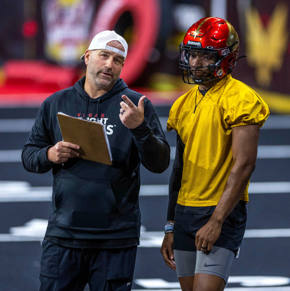 Vegas Knight Hawks head coach Mike Davis talks with his quarterback Daquan Neal during practice ...