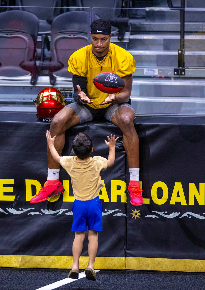 Vegas Knight Hawks quarterback Daquan Neal tosses a ball to a youngster during practice at The ...