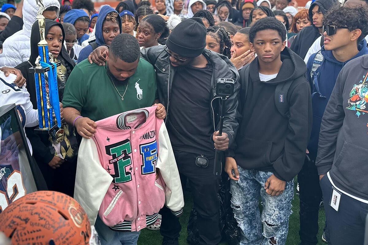 Jeremiah Wiggins, 35, center, has an arm around Quan Britton, 23, at a vigil for Omarion Wilson ...