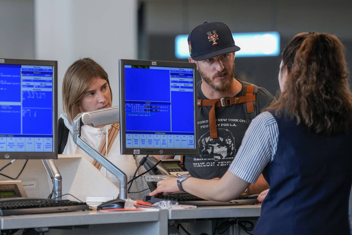 A airline agents helps a travelers in the departures area of Terminal B at LaGuardia Airport, T ...