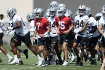Raiders quarterbacks Brian Hoyer (7) and Chase Garbers (15) lead the team out of a huddle durin ...