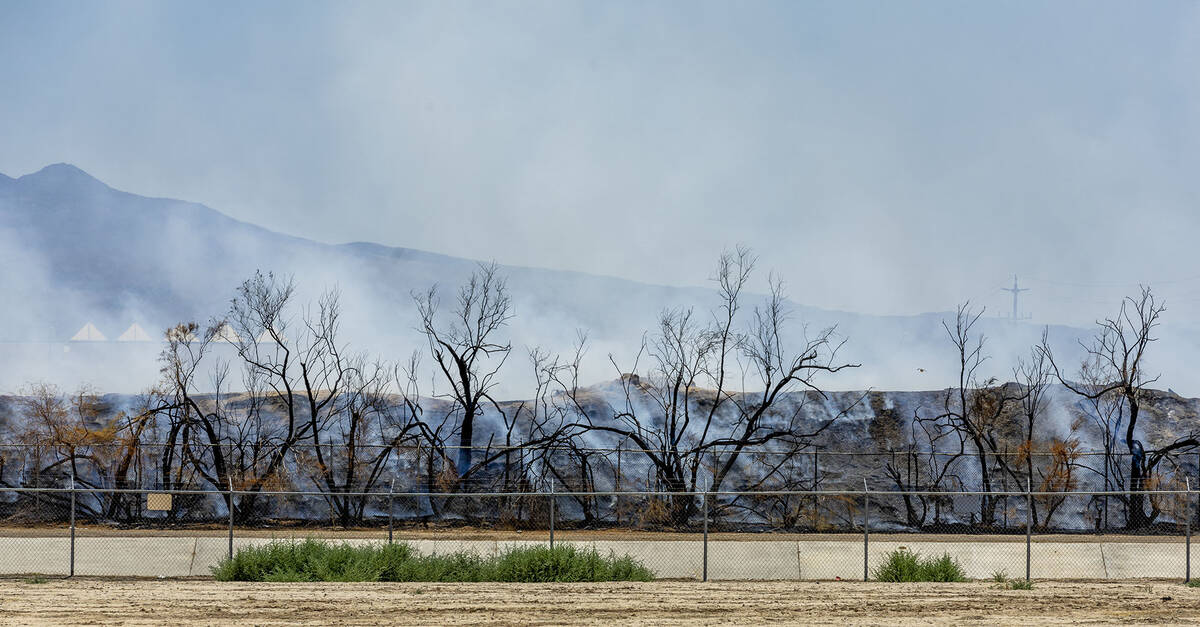 Clark County firefighters extinguish a brush fire adjacent to the Las Vegas Wash along the far ...