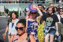 A woman in a crowd shields her face from the sun on the Strip on Thursday, June 29, 2023, in La ...