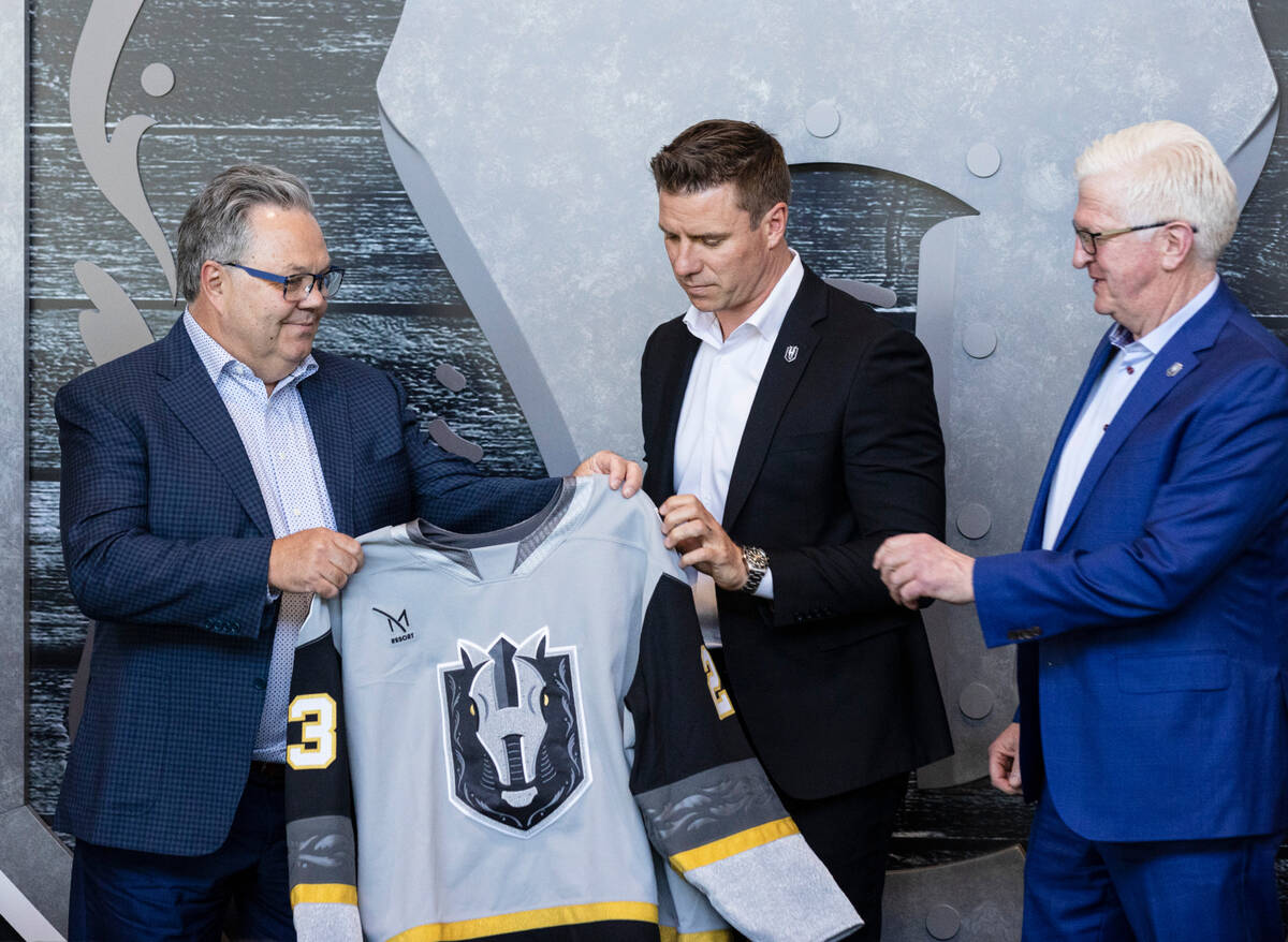 Golden Knights General Manager Kelly McCrimmon, left, presents a jersey to Ryan Craig as Tim Sp ...
