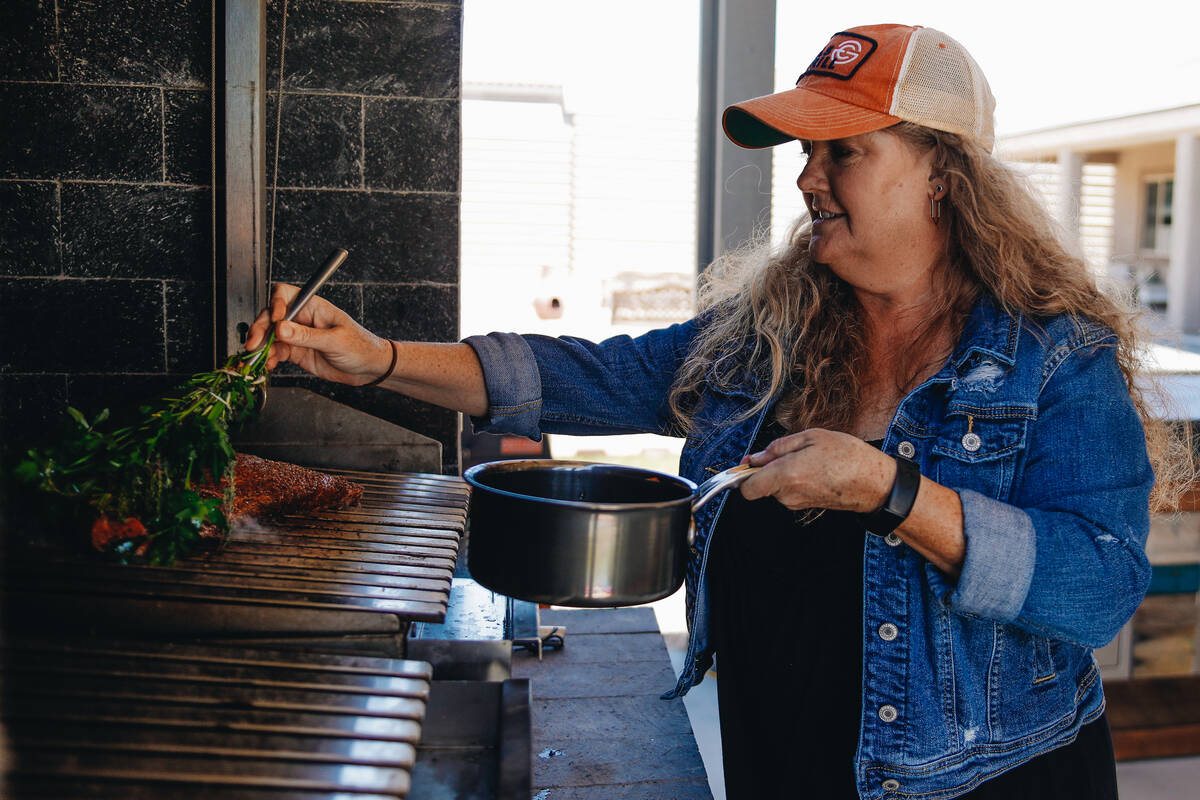 Christie Vanover bastes her barbecue with a brush made of herbs on Friday, June 30, 2023, at he ...