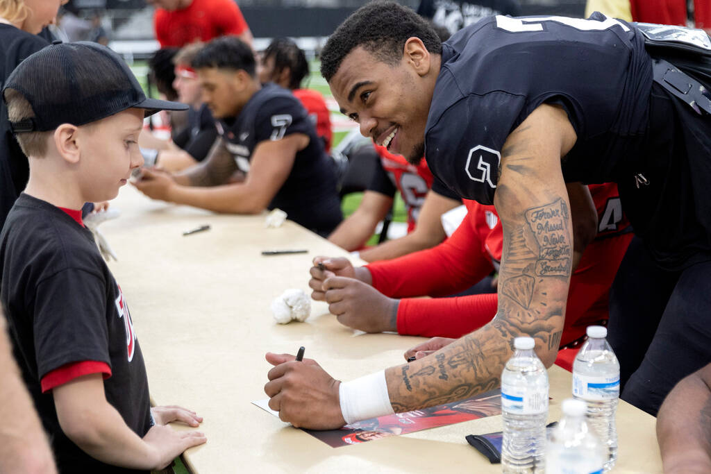 Quarterback Doug Brumfield signs an autograph for Rebels fan Elijah Barnum, 9, during the UNLV ...