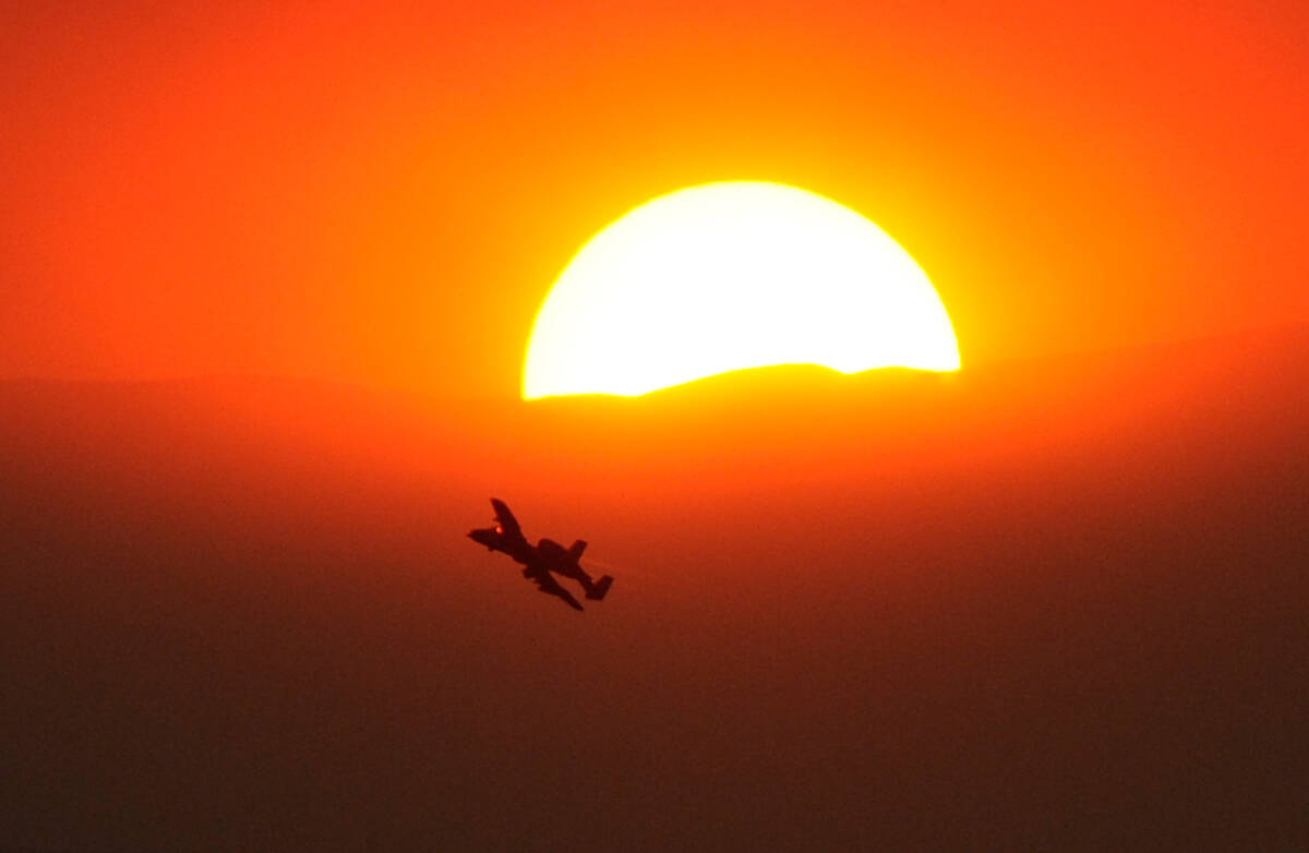 An Air Force A-10 is seen flying by the partially obscured sun from smoke from the Carpenter 1 ...