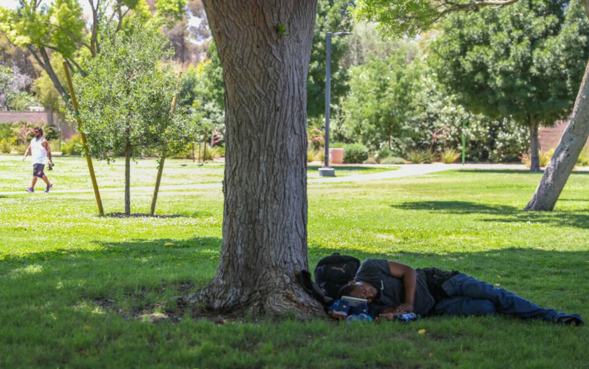 A man rests in the shade underneath a tree at Bob Baskin Park to cool down during the 110 degre ...