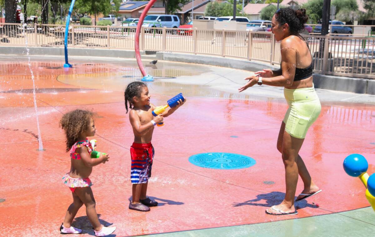 Zayn Clark, 3, and Zuri Clark, 2, play with water guns alongside their mother, Ashley Clark, to ...
