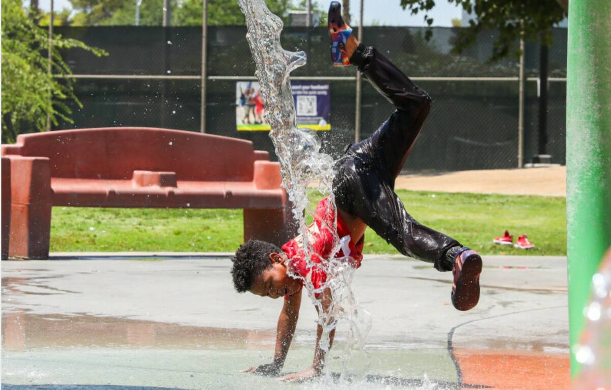 Trent Turner, 7, jumps through the water features at Bob Baskin Park to cool down during the 11 ...
