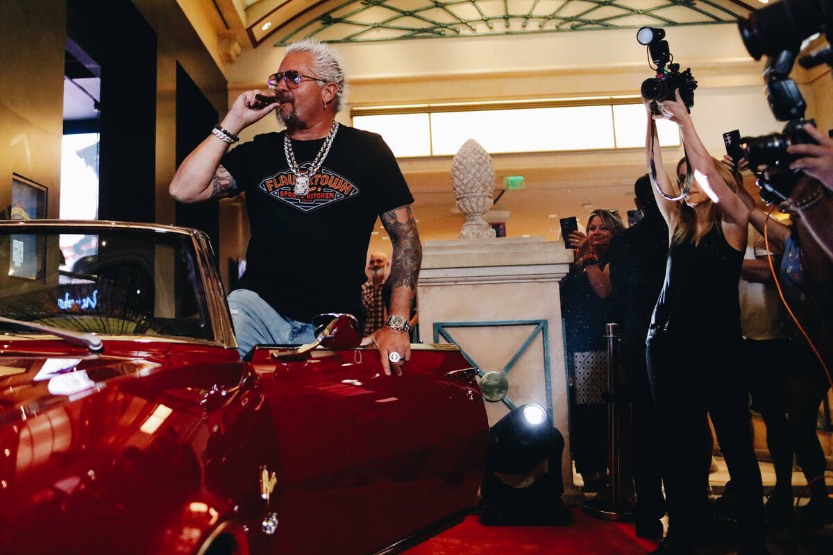 Guy Fieri smokes a cigar inside of a car parked outside of his new restaurant on Friday, July 7 ...