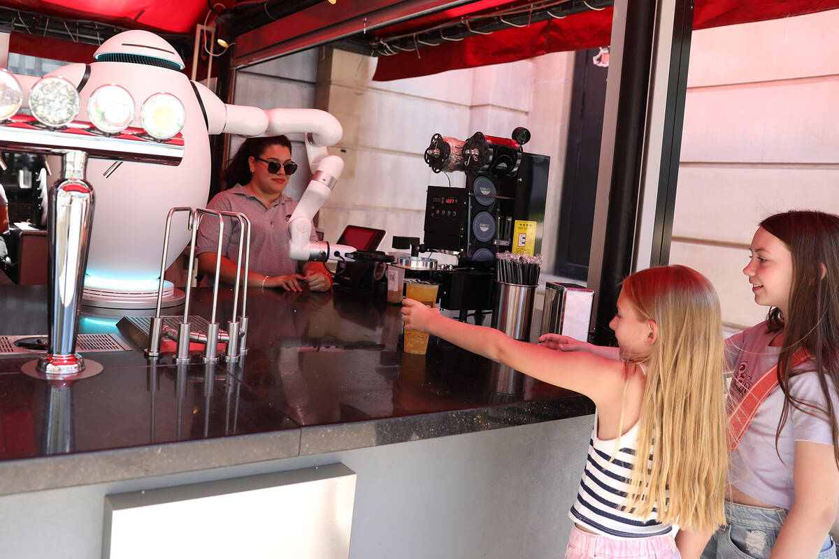Reagan Lorentzen, left, and Ruby Jo Kohler are handed their teas from Adam the robot at Cloutea ...