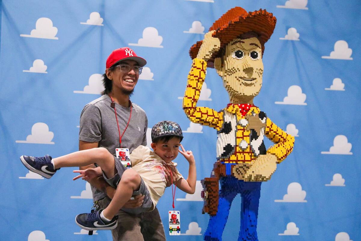 Jesus Lugo holds Zeppelin Lugo, 5, in front of a giant Woody made out of LEGO bricks at the Bri ...