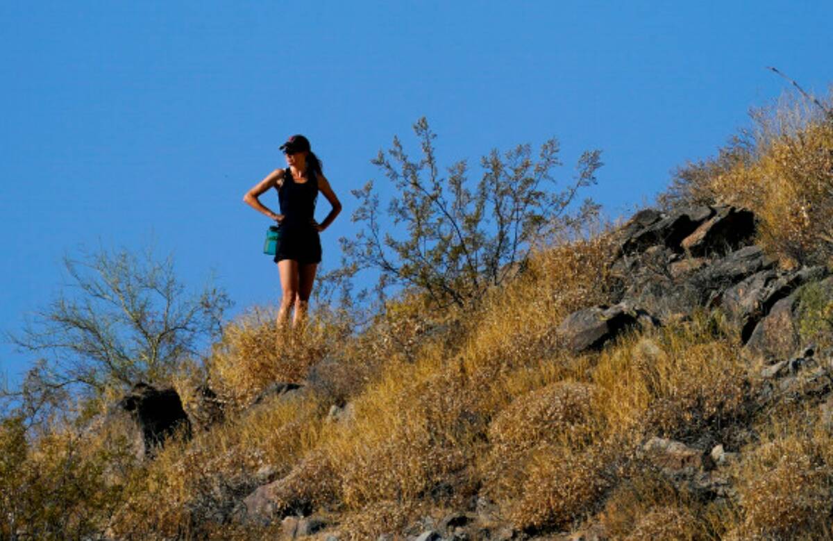 A hiker pauses during her hike early Monday, July 10, 2023, in Phoenix. (AP Photo/Matt York)