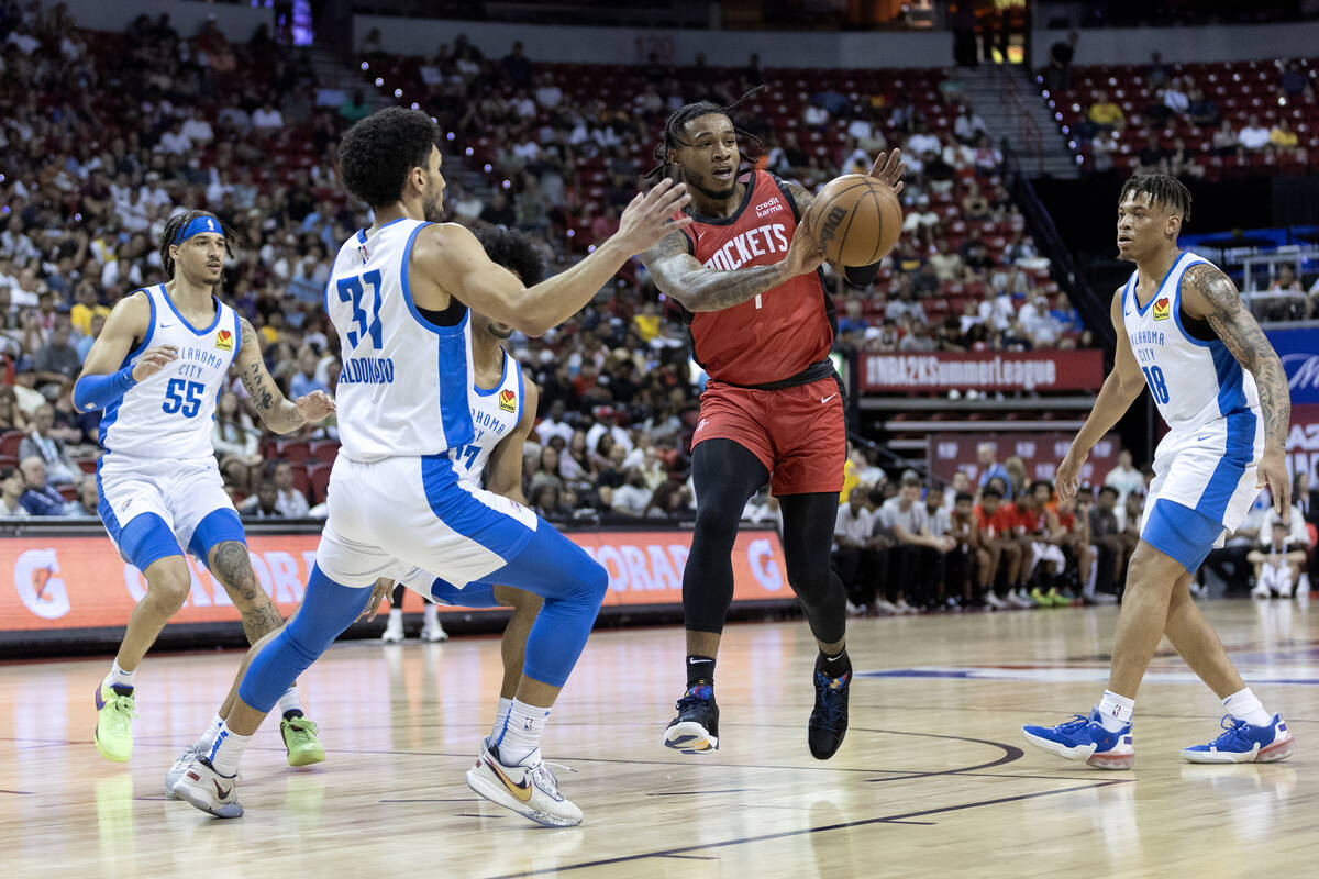 Houston Rockets forward Cam Whitmore, center right, passes while Oklahoma City Thunder guard Ca ...