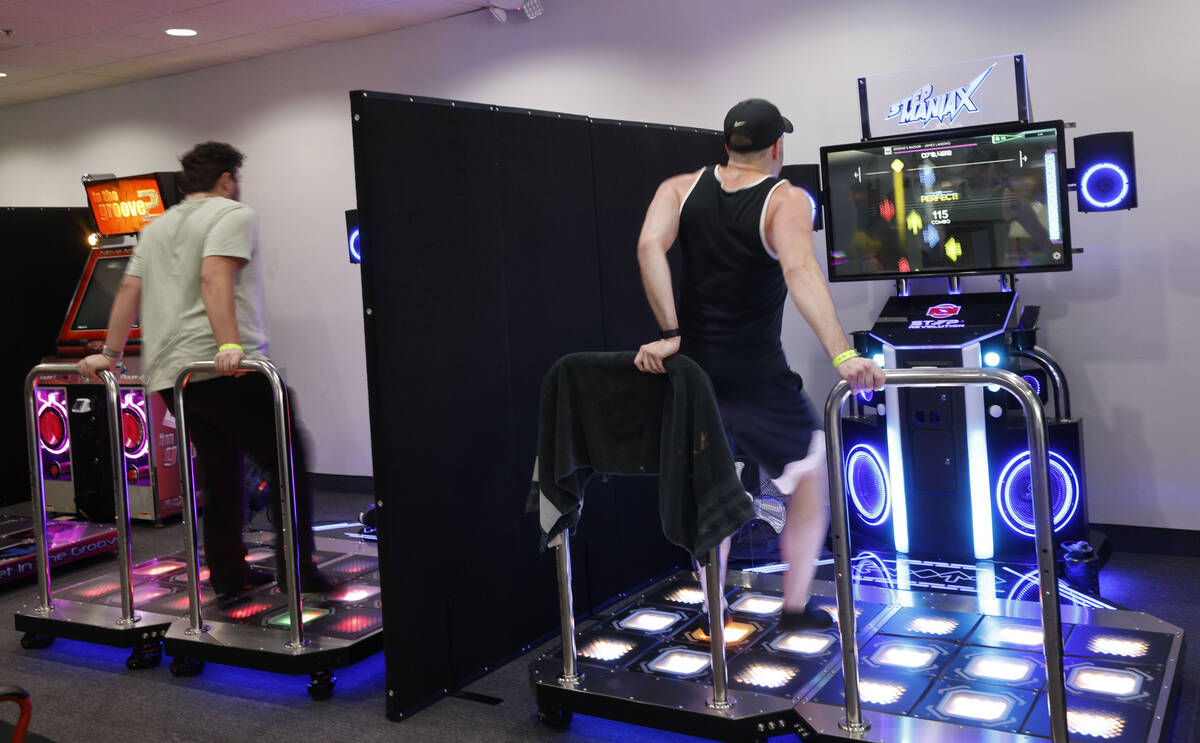 Justin Kuret of Las Vegas, right, shows off footwork as he plays StepManiaX, a rhythm game, at ...