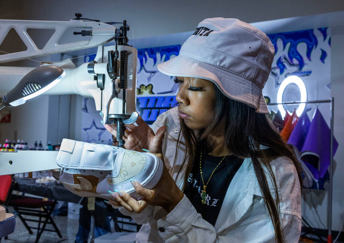 Nikki Roxas sews a custom pattern to a sneaker in the Majorwavez Lab booth on the concourse dur ...