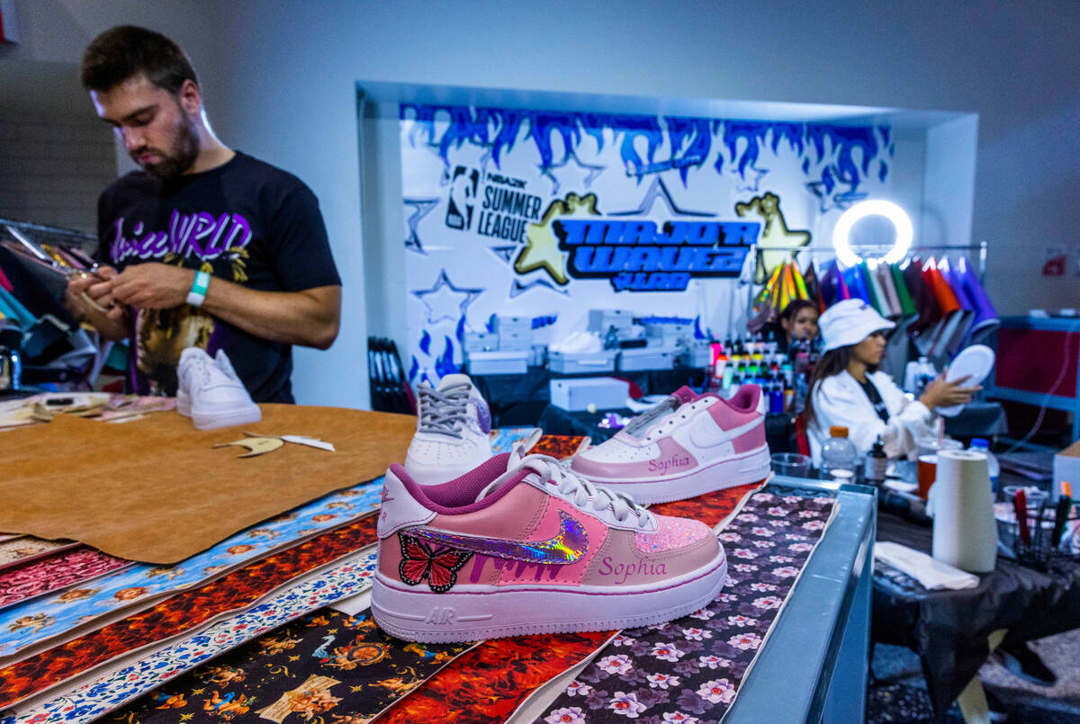 Colin Szumski, left, cuts out custom patterns for sneakers as Nikki Roxas, right, attaches them ...