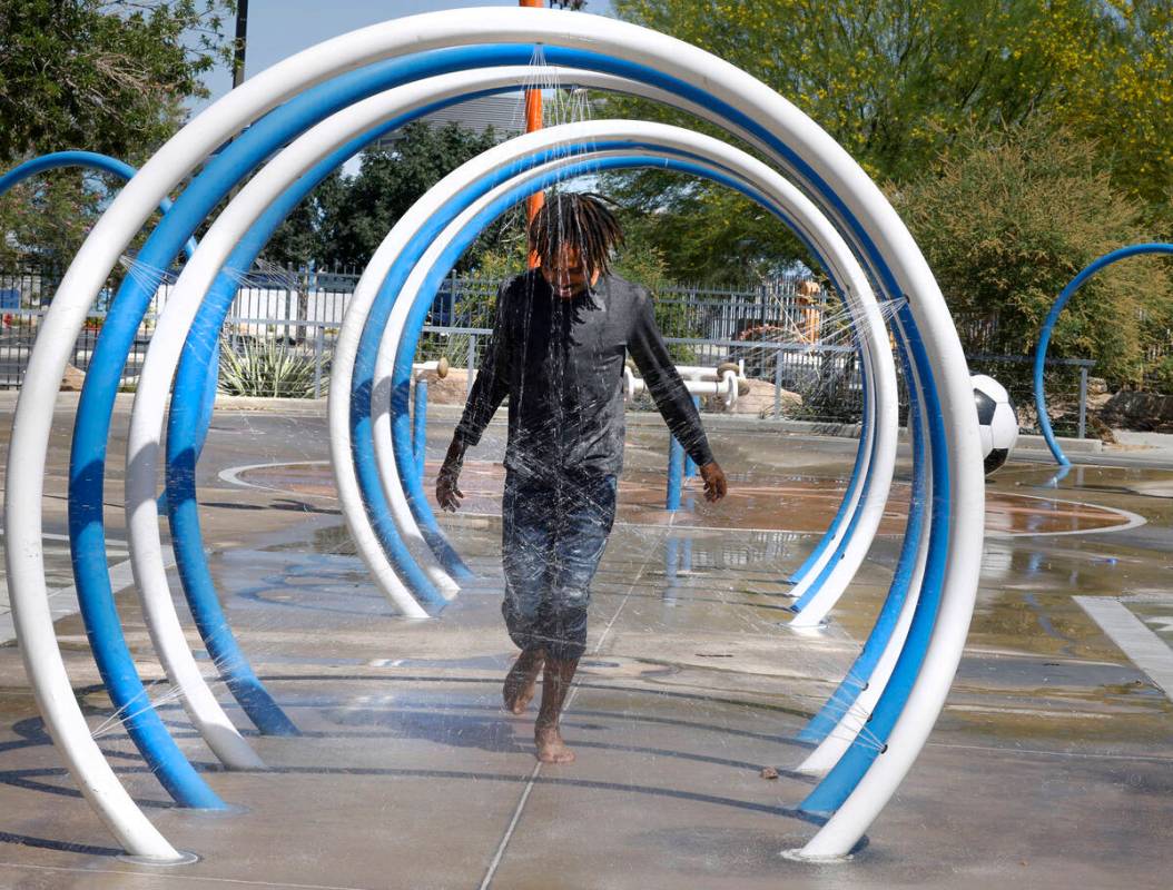 Samuel Lee Jones of Las Vegas runs through the water at Baker Park’s splash pad, Friday, ...