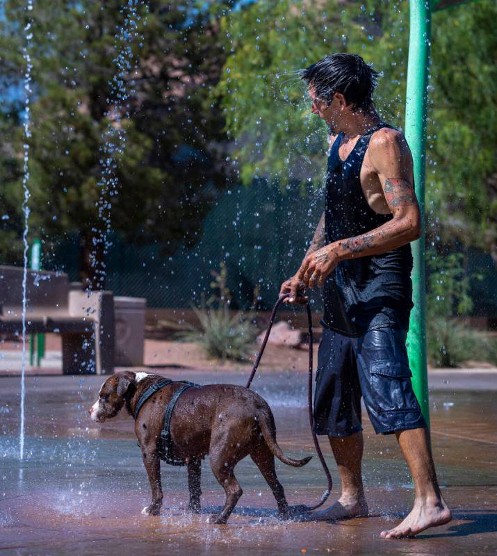 Robert Fralick and his dog Koko cool off from the heat is the fountains at Bill Briare Park as ...