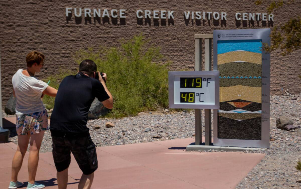 People stop to take photos of a thermostat reading 119° Fahrenheit (48° Celsius) at the Furna ...