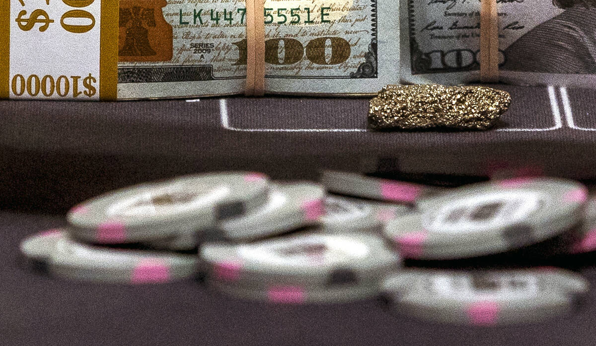 A piece of fool's gold piece on the table with cash and cards on the final day at the World Ser ...