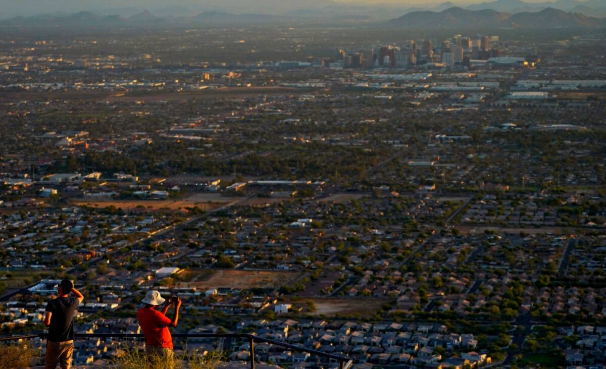 Hikers photograph the sun rising over Phoenix atop South Mountain, Monday, July 17, 2023. (AP P ...