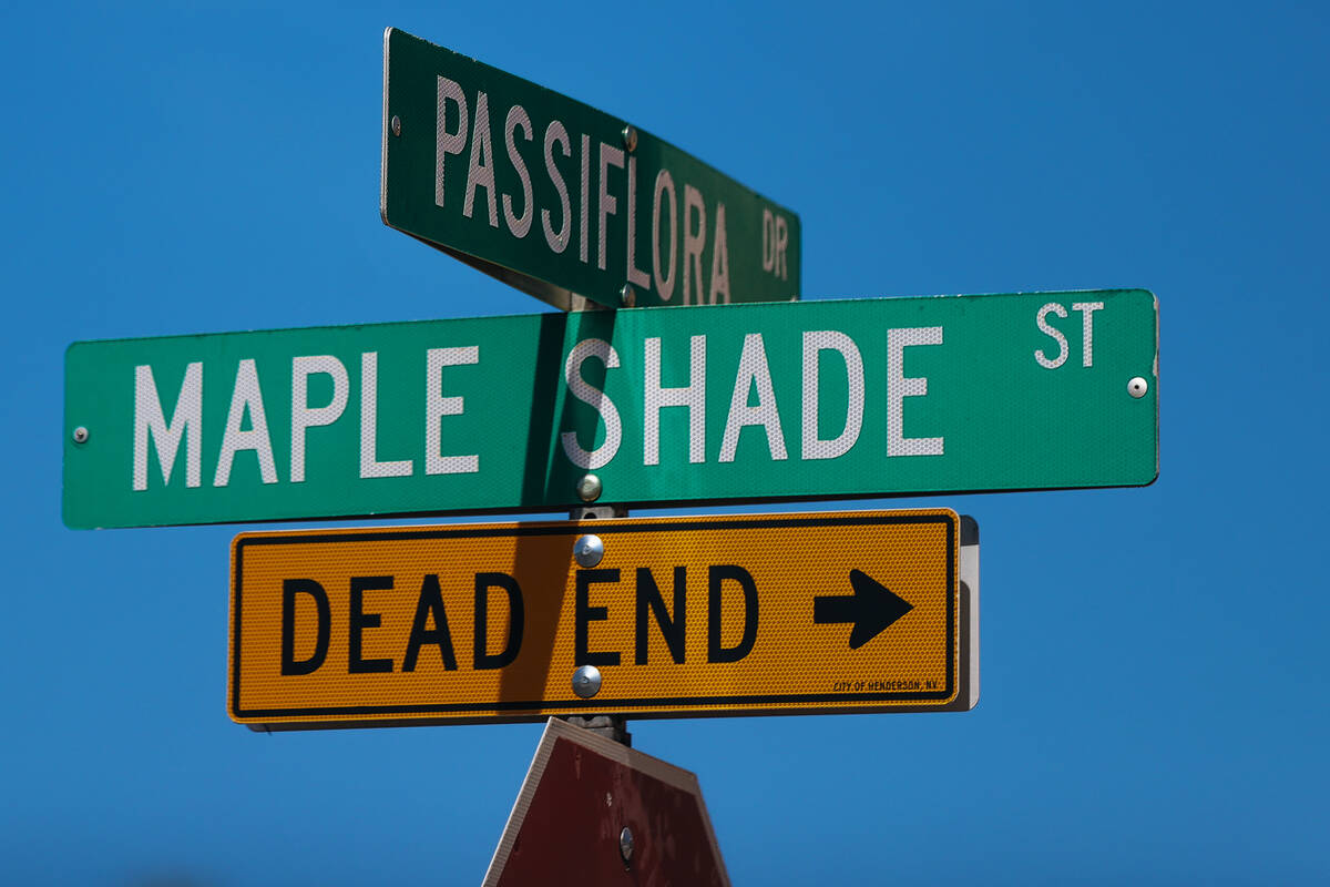 A street sign for Passiflora Drive and Maple Shade Street are seen on the same block as a house ...