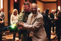 Earl White, front, smiles as he gets to try out a taser at an event that allowed people to expl ...