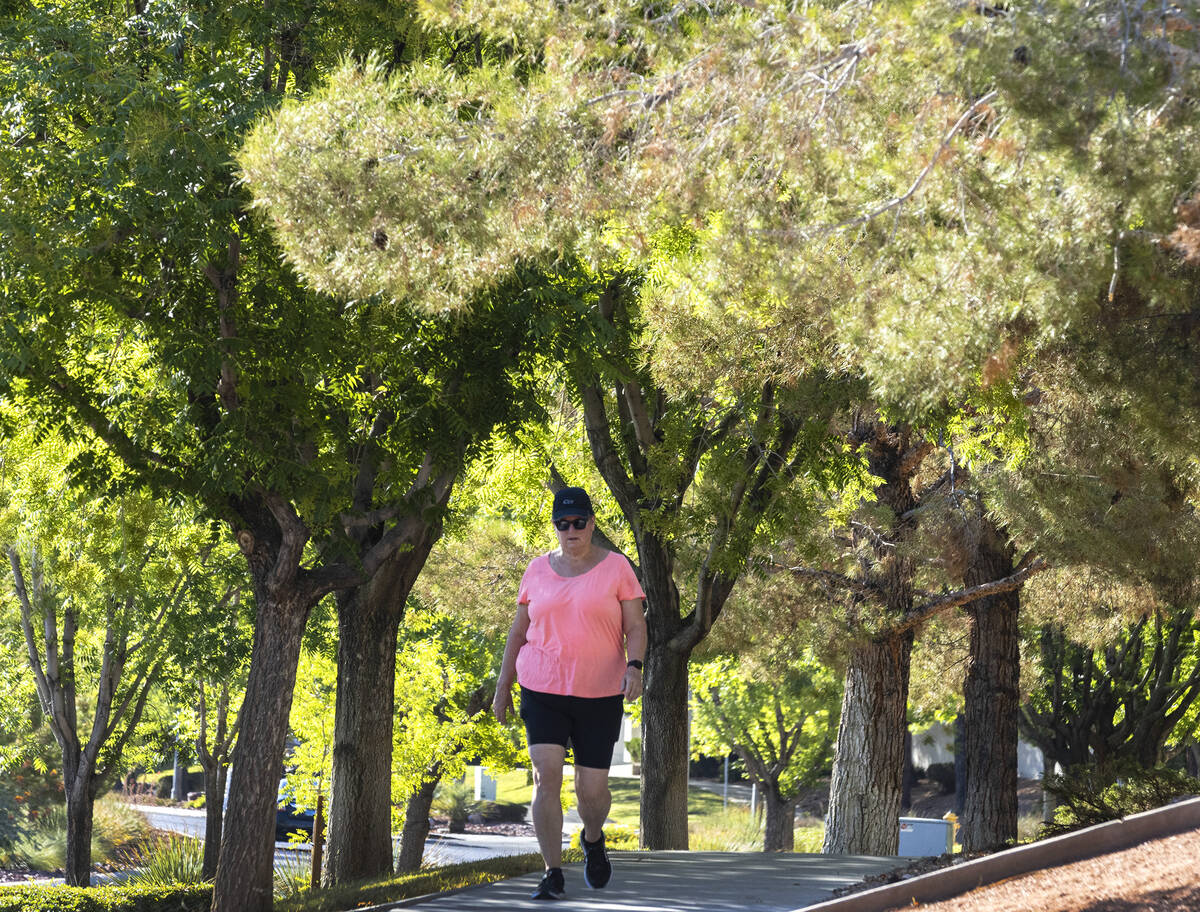 A pedestrian walks on a tree-covered sidewalk along Green Valley Parkway on Thursday, July 20, ...